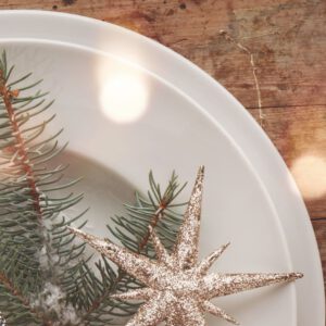 Festlich gedeckter Tisch mit weißem Geschirr und silbernem Stern-Anhänger