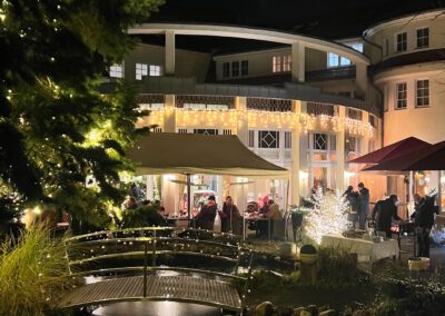Beleuchtete Außenansicht des Wirtshaus Alpinia am Abend mit Gästen