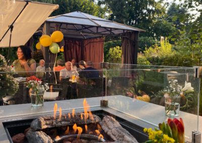 Outdoor-Grilltisch mit Feuerstelle unter der Pergola am Abend