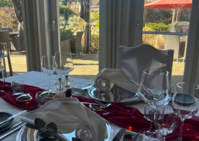 Eingedeckter Tisch im Wintergarten des Wirtshaus Alpinia mit Blick auf die sonnige Terrasse