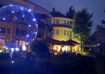 Wirtshaus Alpinia am Abend mit beleuchteter Terrasse und Lichterdekoration