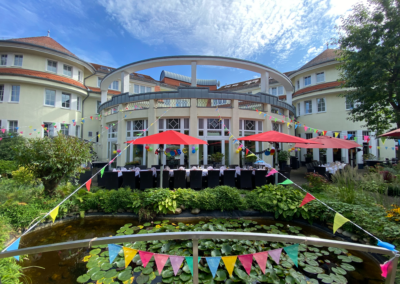 Außenansicht des Wirtshaus Alpinia in Berlin-Mariendorf mit Biergarten und roten Sonnenschirmen