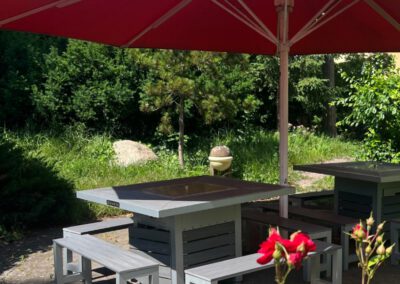 Gemütliche Terrasse mit roten Sonnenschirmen im Wirtshaus Alpinia